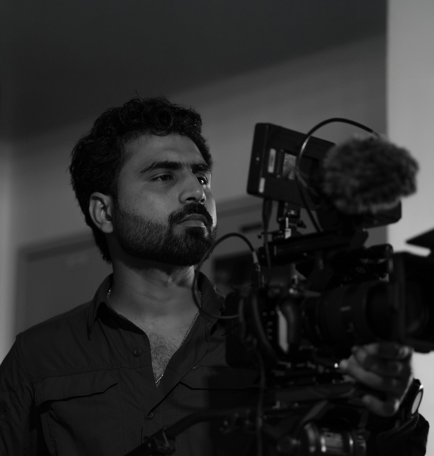 Bilal Ismat operating a professional cinema camera on set (black and white)